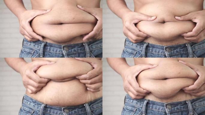 男人的手握着过多的腹部脂肪，超重的概念