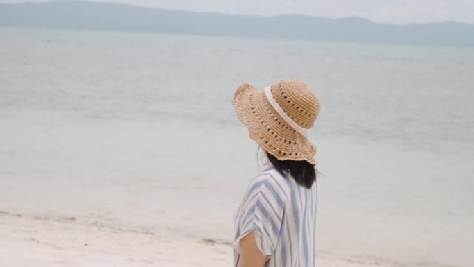 亚洲女人暑假在海滩上散步，情绪平静。独自旅行