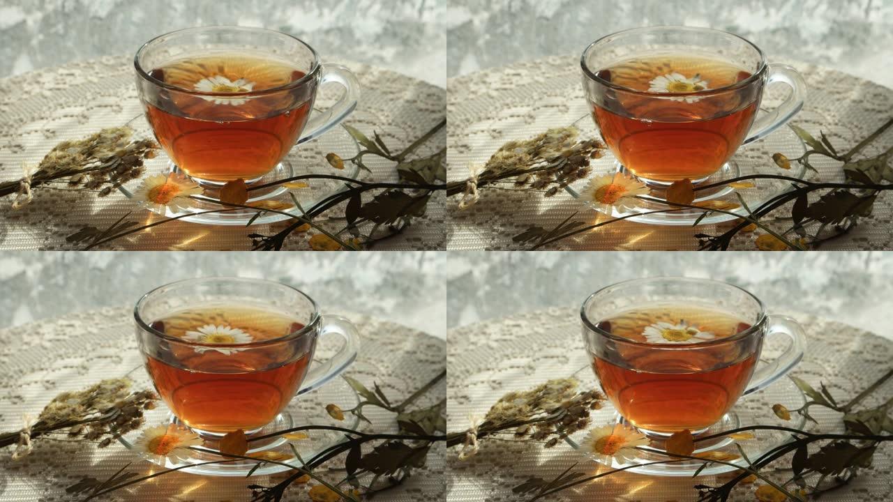 洋甘菊花漂浮在冰霜的窗户上的凉茶玻璃杯中