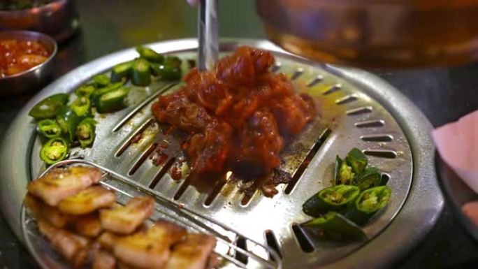 4k厨师在烧烤木炭烤架上手工烹饪猪肉片和韩国红酱。