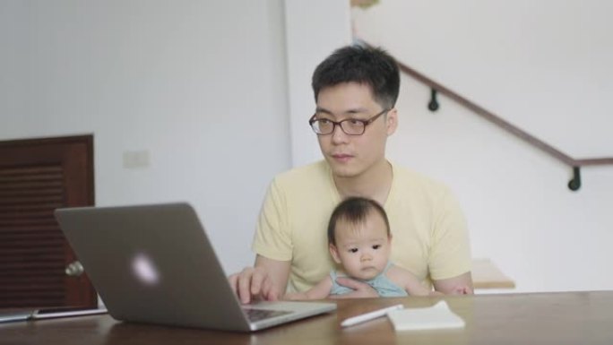 泰国父亲抱着婴儿女儿在家工作