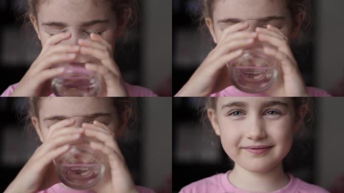 可爱的小女孩在家喝玻璃新鲜透明纯过滤矿泉水。慢动作小女孩喝水。特写儿童饮水杯健康身体护理。健康生活方