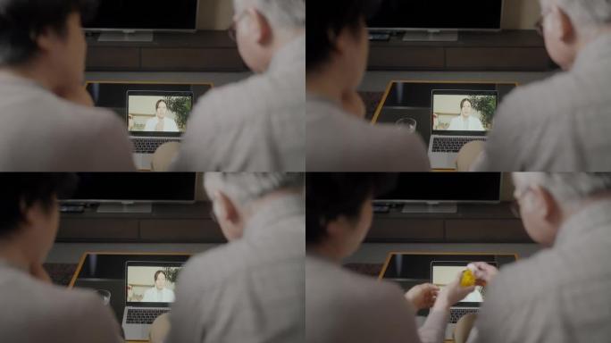 已婚老年夫妇在家客厅与女医生在笔记本电脑上视频通话会议