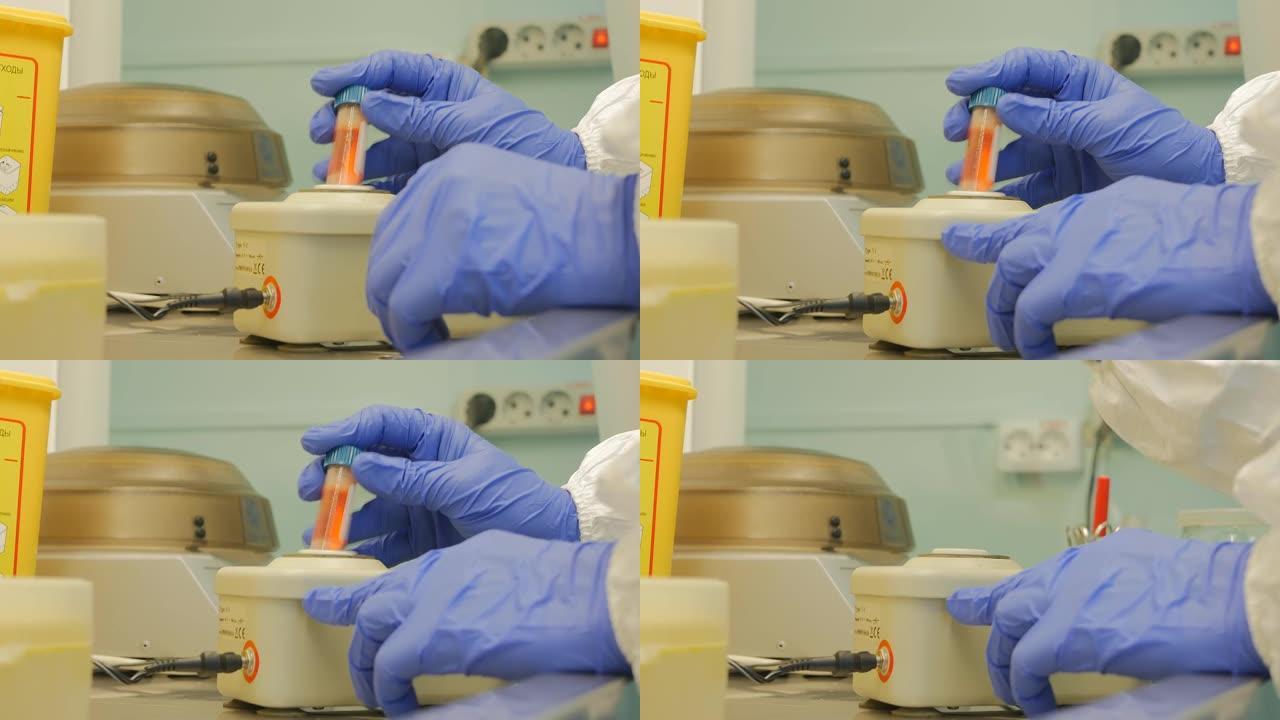 一位女生物学家将一小瓶血清插入用于搅拌的特殊装置中并将其打开。试管开始剧烈振动。