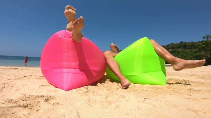 一对夫妇躺在海滩上的充气沙发上享受闲散