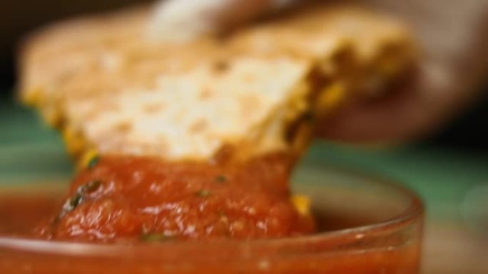 新鲜油炸的热蔬菜玉米饼浸泡在莎莎酱中的宏观视图。制作墨西哥玉米饼的过程