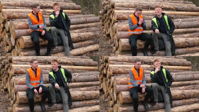 工人暂停记录工作。他们坐在木头上，抽烟。