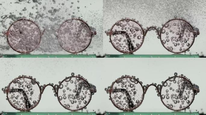 一股苏打水倒在水中的圆形玻璃杯上，引起氧气气泡的涡旋。白色背景上的水中眼镜。慢动作。特写