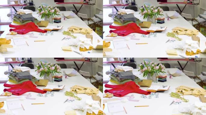 阳光时装设计工作室的照片，桌子上有各种缝纫相关物品和彩色织物