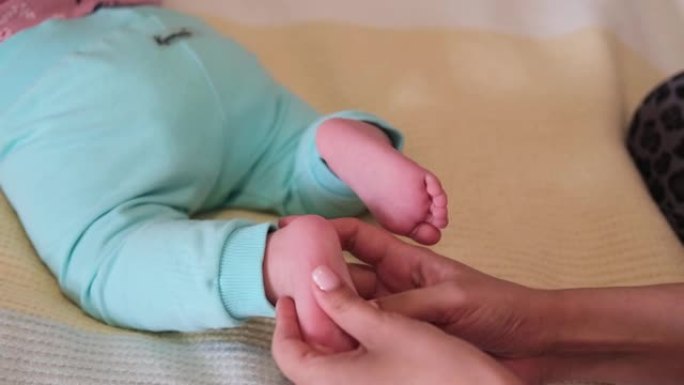 对新生婴儿做足部按摩的女性双手特写。妈妈给孩子按摩。医疗保健，家庭程序。