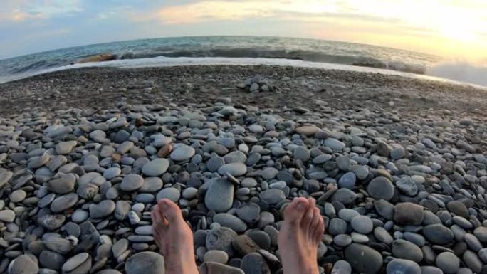 男性的腿在海滩上被鹅卵石覆盖着，靠海