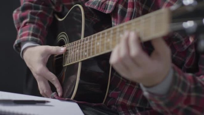 音乐家在书写和演奏原声吉他后放下笔的中等镜头