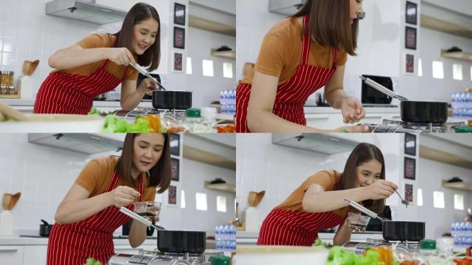 亚洲女性在家里的厨房里烹饪和学习数字平板电脑