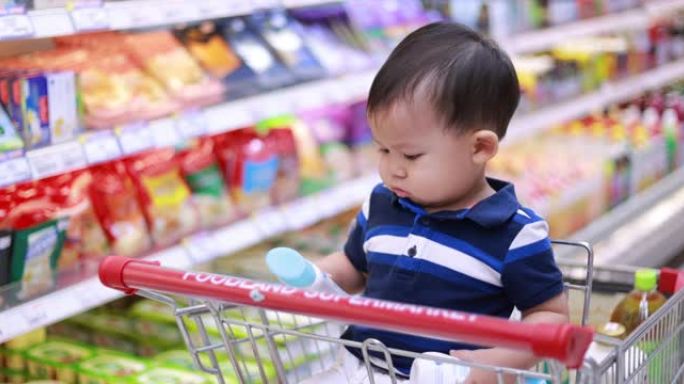 亚洲男婴坐在购物车里买杂货