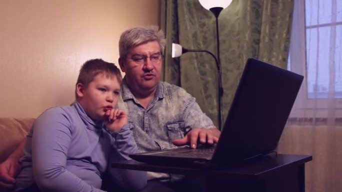 男孩和他的父亲在家在线学习，观看和听课。