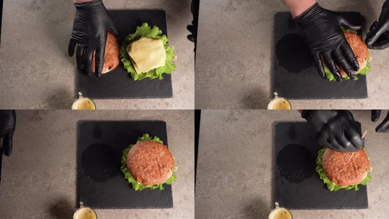 厨师准备三明治。厨师的手准备一个美味的双汉堡的特写镜头，将奶酪放在牛肉排上，然后在上面放一个芝麻面包