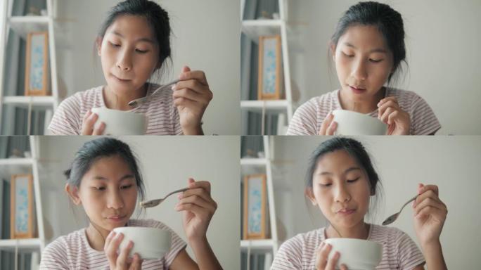 快乐的亚洲女孩在家窗口附近吃冰淇淋，生活方式理念。