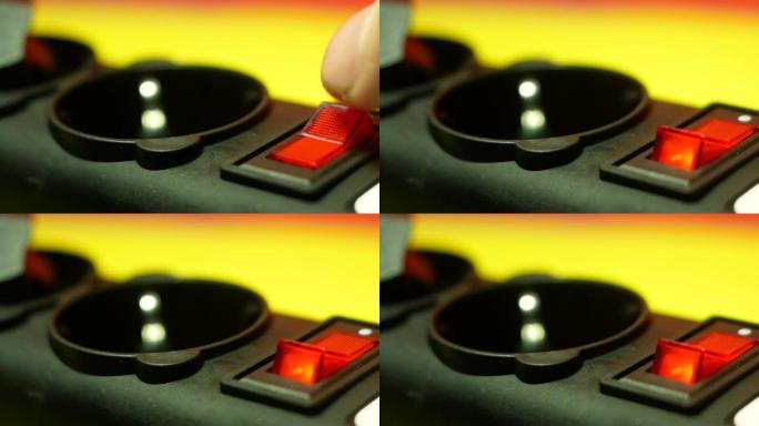 手指的特写打开电器的红色按钮。红色按钮为220伏电源滤波器。选择性聚焦，浅景深