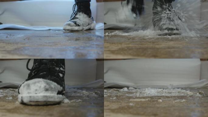 一个人的脚甩掉了鞋子上的雪，在地板上用力踩踏。特写。冬天，大雪纷飞。元素。
