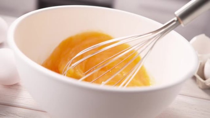 用打蛋器在白碗中搅拌蛋黄，以慢动作搅拌蛋卷
