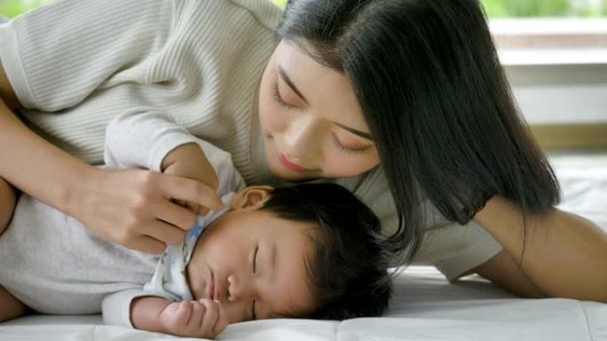 年轻的亚洲妈妈在家照顾新生儿。