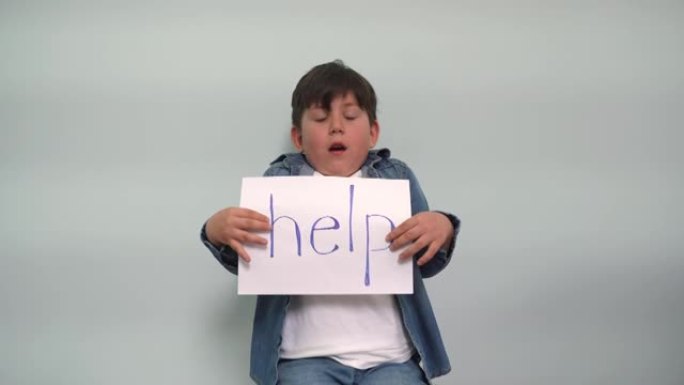 一个看上去很害怕的男孩拿着一张纸，上面写着 “帮助” 字样。欢快的孩子在灰蓝色背景上显示了一个带有 