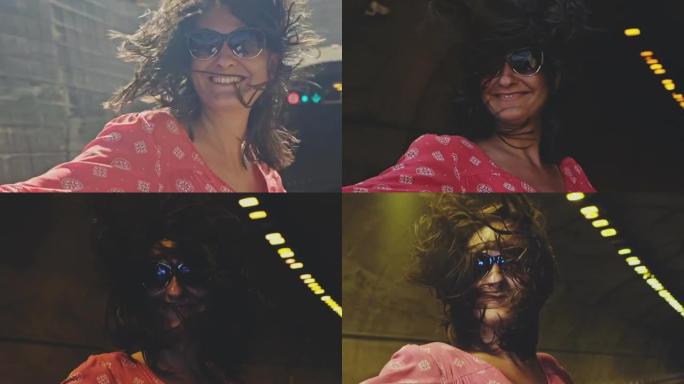 戴着太阳镜的女人在敞篷车中以我们在公路隧道中行驶的速度感到高兴。风扇动她的头发。慢动作