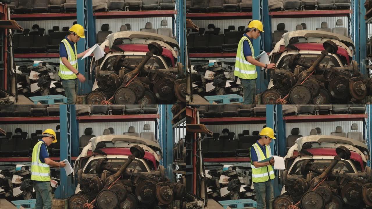 穿着安全制服和黄色头盔的亚洲男性工人。在仓库工厂检查汽车工业业务中的备件库存，例如发动机，汽车座垫和