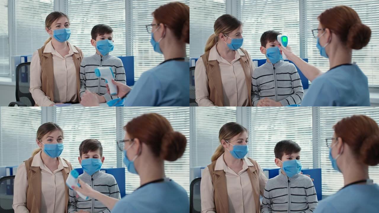 女医生在医院预约时用口罩咨询男孩和母亲，治疗师用非接触式温度计测量小病人的体温