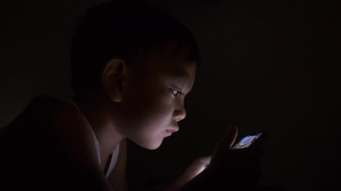 小男孩晚上使用智能手机
