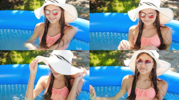 戴着夏日帽子和太阳镜的微笑年轻女孩的肖像在室外游泳池放松。暑假和假期