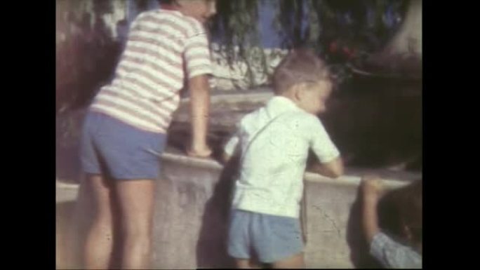 孩子们试图爬上一堵小墙，走在海边1959年8毫米FDV