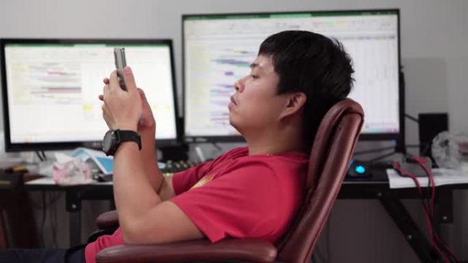 亚洲男人在用电脑工作时感到无聊。