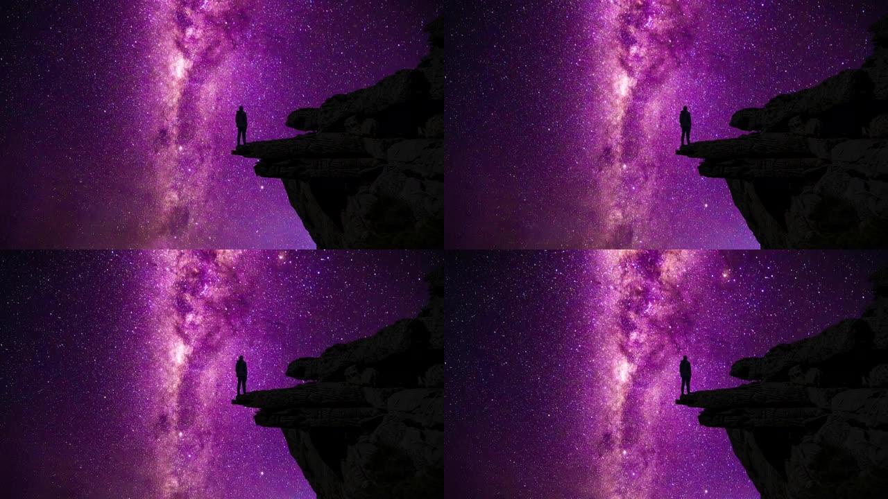 站在悬崖边欣赏银河和流星的男人的剪影