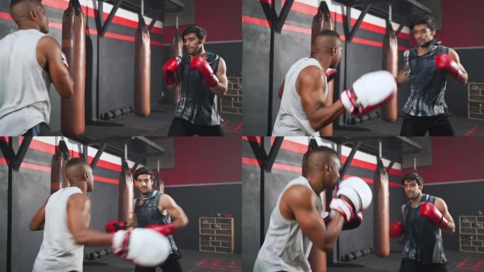 英俊的斗士男子戴着拳击红色手套，在健身运动健身房与教练一起拳击。在室内与教练一起训练拳击。练习和练习