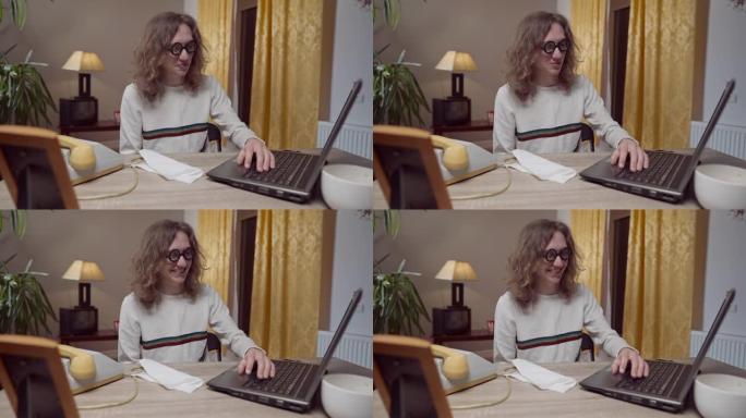 年轻的书呆子20世纪80年代20世纪90年代男人用老式过时的笔记本电脑在桌子下移动手。高加索极客的中