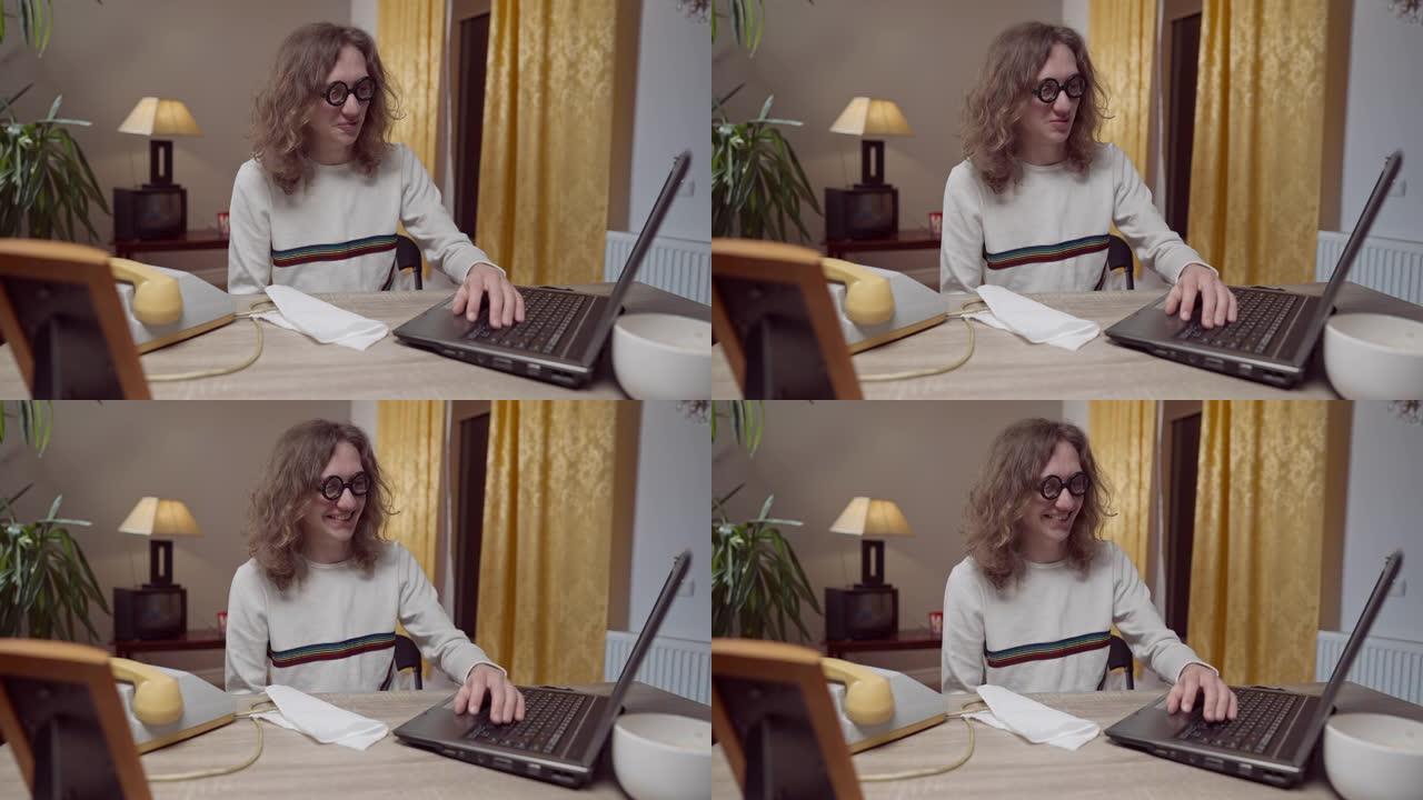 年轻的书呆子20世纪80年代20世纪90年代男人用老式过时的笔记本电脑在桌子下移动手。高加索极客的中