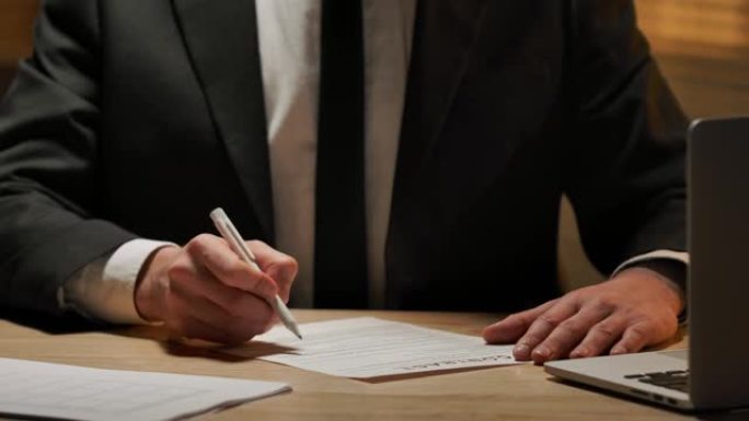 商人用笔检查并签署合同。穿着西装的老板坐在办公室的桌子旁。签署文件、协议或交易、批准伙伴关系。特写。