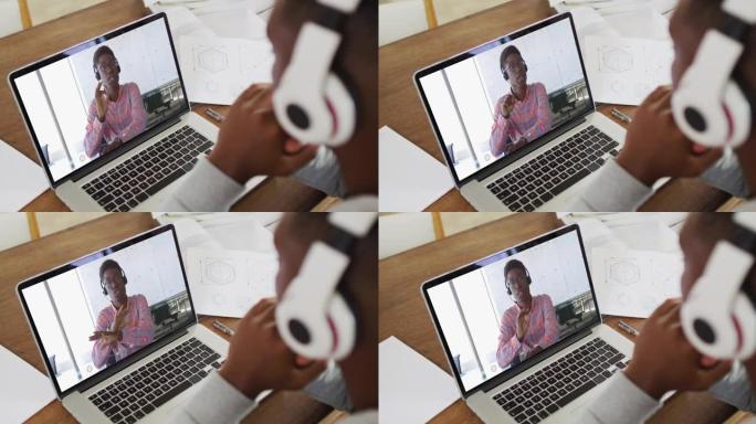非裔美国男大学生戴着耳机在家里的笔记本电脑上进行视频通话