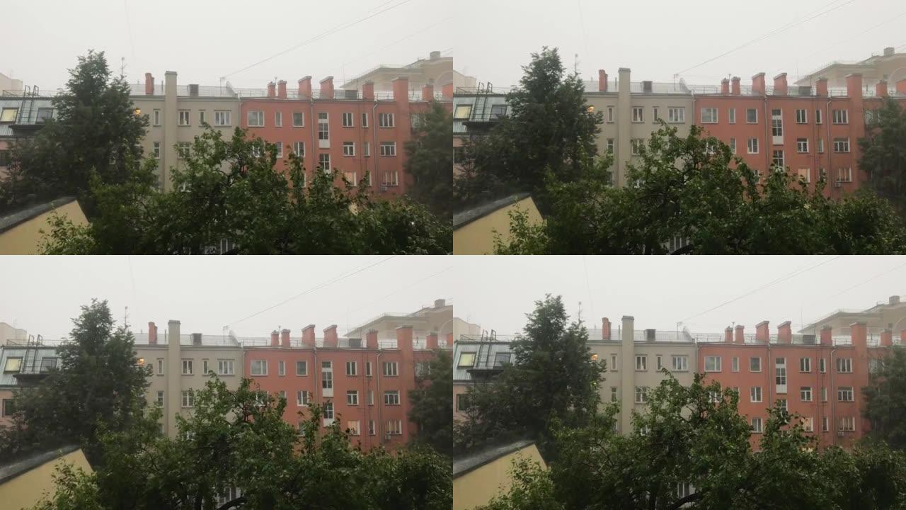 从窗户到最强烈的倾盆大雨的景色。窗外，绿树成荫，城市的居民楼