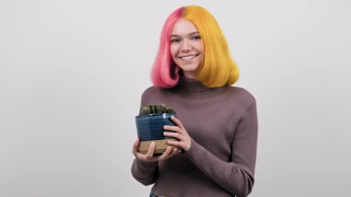 微笑快乐的少女，染成彩色头发，带仙人掌室内植物