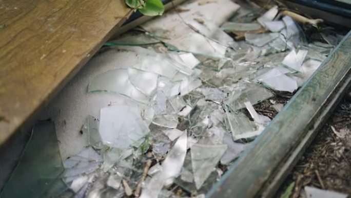 玻璃破碎破碎的窗框躺在地上。附近的废弃建筑