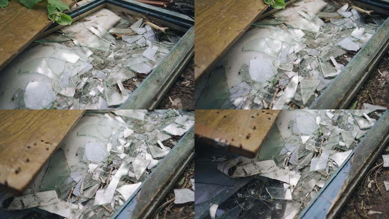 玻璃破碎破碎的窗框躺在地上。附近的废弃建筑