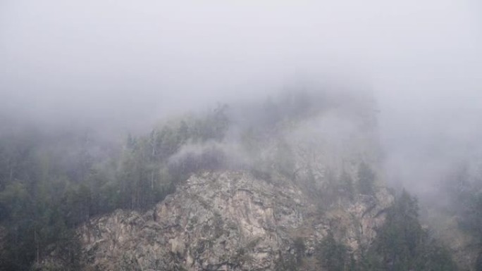 延时陡峭的山坡上覆盖着永恒的绿色森林，上面铺着低云的积雪。山区4k云运动