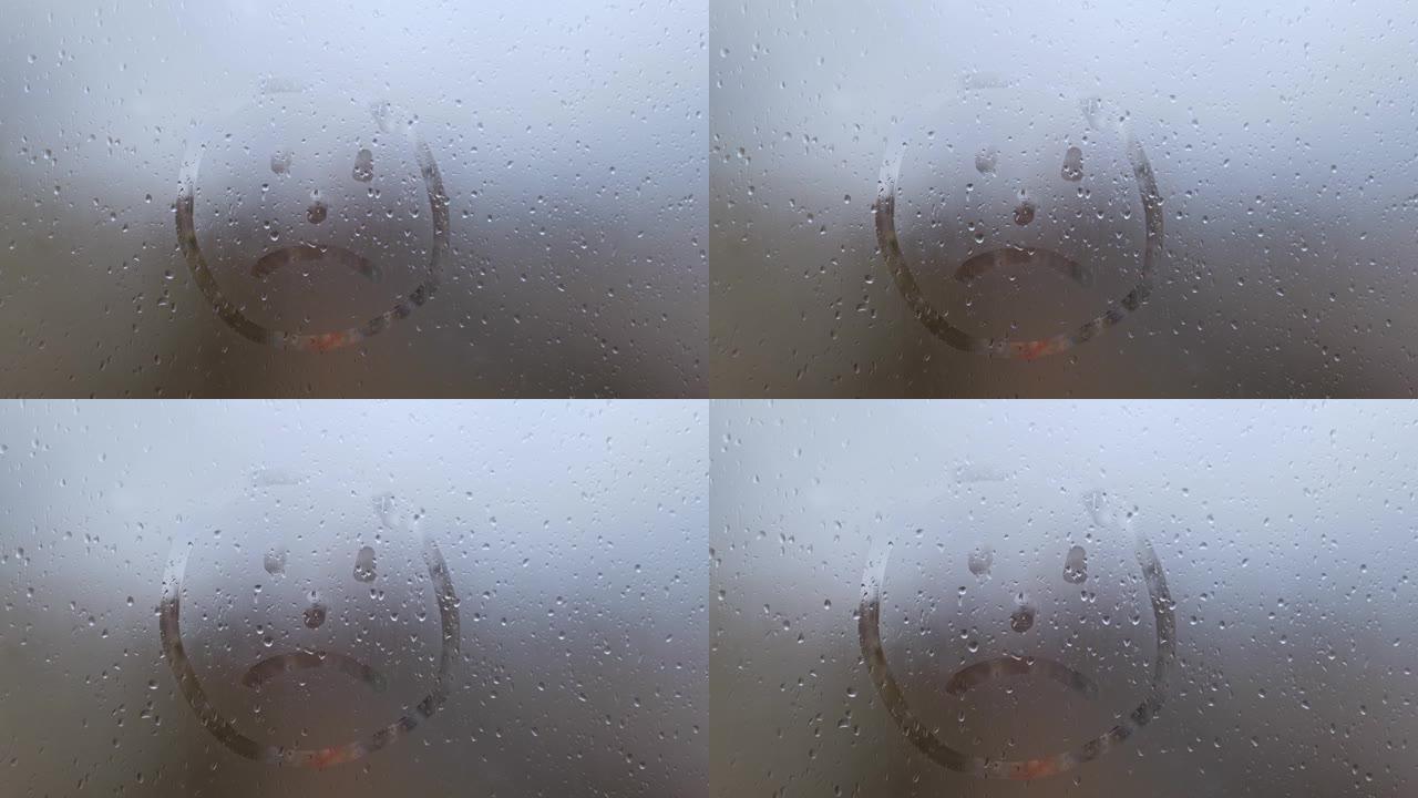 在雾蒙蒙的玻璃上画一张悲伤的脸。快乐心情和悲伤的象征