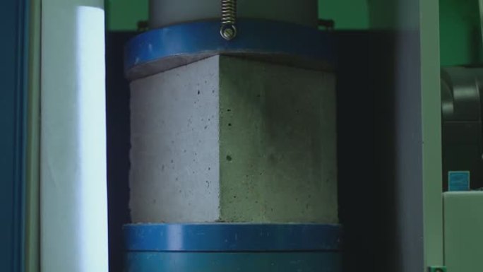 混凝土块在高压下断裂。液压机正在对混凝土制成的立方体产生压力。强度测试。混凝土立方体抗压强度试验。在