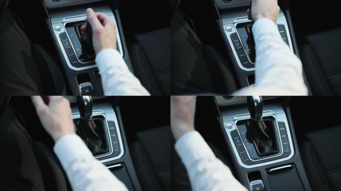 男性换档驾驶汽车。驾驶员控制自动并切换档位，然后换到空档并拉动手刹手柄