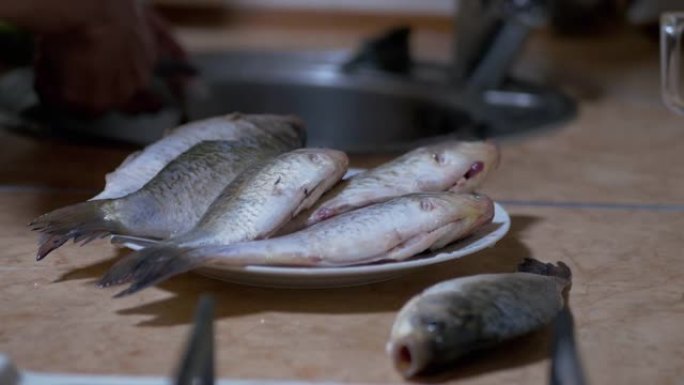 雄性手将新鲜的鱼内脏，放在盘子和桌子上。4K