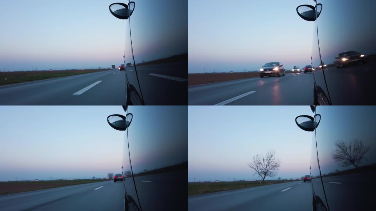 普通汽车在高速公路日落时驾驶POV，迎面而来的交通反映在车身上。从外部4k实时没有人的左侧观点