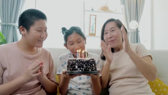 快乐的亚洲家庭在家一起用巧克力蛋糕庆祝女孩的生日，生活方式理念。